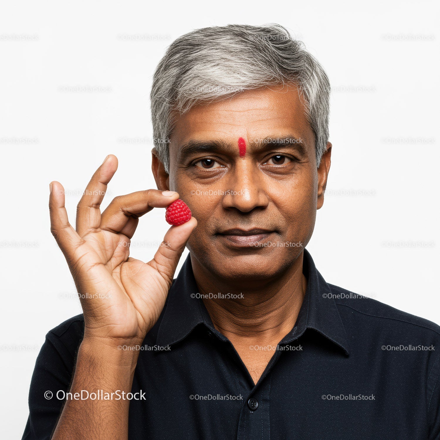 Mature Indian Man Holding Raspberry in Front of White Background