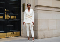 Confident woman in stylish white suit near elegant door