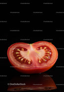 Fresh ripe tomato half on reflective black surface