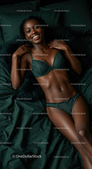 Smiling woman relaxing in elegant green lingerie on bed