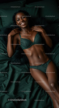 Smiling woman relaxing in elegant green lingerie on bed