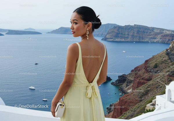 Elegant woman in yellow dress overlooking sea cliff