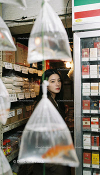 Thoughtful woman surrounded by hanging fish bags in store