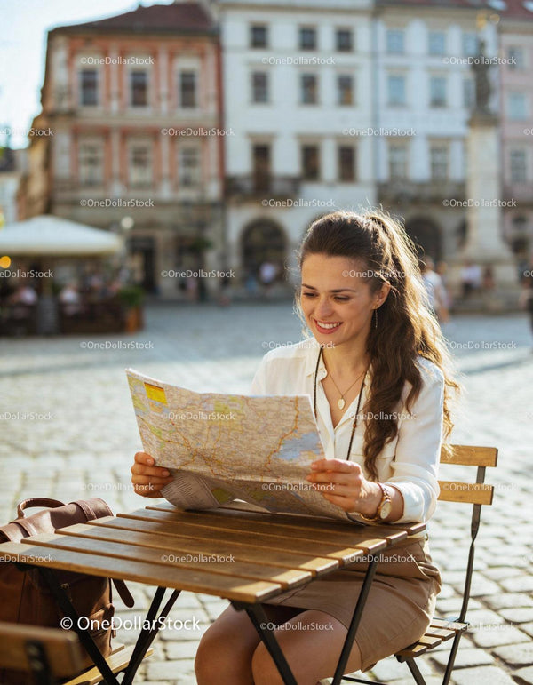 Uśmiechnięta kobieta odkrywająca mapę miasta w kawiarni na świeżym powietrzu