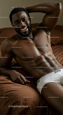 Smiling man relaxing on bed in white underwear