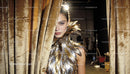 Model Wearing Metallic Feather Outfit Behind Velvet Curtain