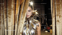 Model Wearing Metallic Feather Outfit Behind Velvet Curtain