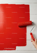 Red Paint Being Applied with Roller on White Wall for Home Renovation