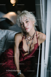 Stylish Blonde Woman in Red Satin Top with Layered Jewelry Indoor