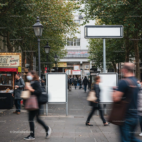Busy urban walkway with blurred pedestrians and blank signs JPG Mockup Image