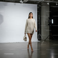 Young woman walking in oversized knitted sweater indoors