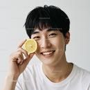 Young Man Smiling with Lemon Slice in Bright Indoor Setting