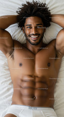 Smiling muscular man relaxing on bed in white underwear