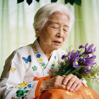 Elderly woman in traditional attire holding purple irises