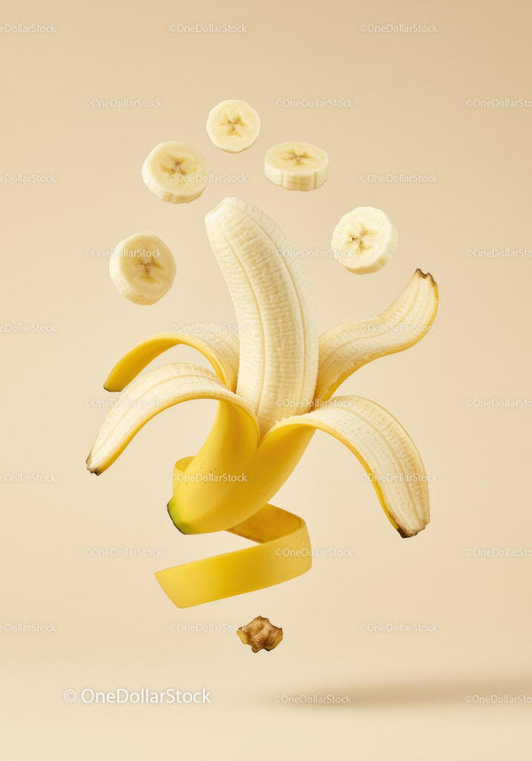 Peeled banana with floating sliced pieces on beige background