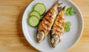 Grilled Sardines with Cucumber Slices and Fresh Herbs on White Plate