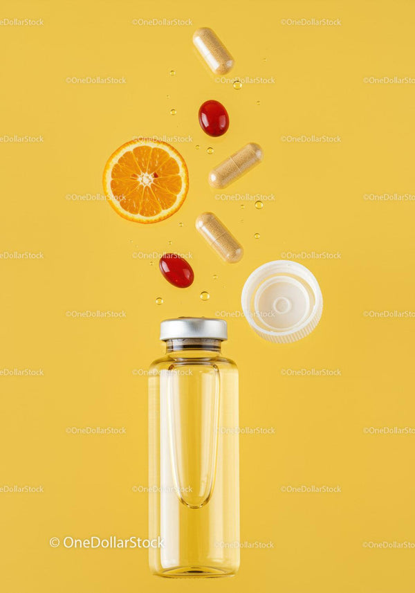 Supplements and fresh orange slice with liquid bottle