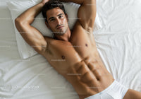 Relaxed shirtless man lying on white bed