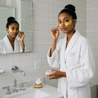 Woman Applying Gold Eye Patches in Bathroom Mirror for Skincare Routine