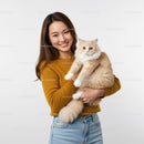 Young woman joyfully holding fluffy cream cat