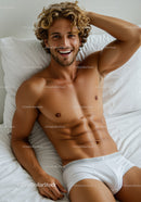 Smiling man with curly hair relaxing on white bed