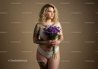 Young Woman with Tattoos Holding Purple Flowers in White Lingerie