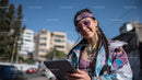 Young Woman in Colorful Jacket Smiling with Smartphone in Urban Setting