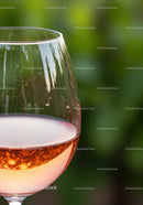 Glass of rose wine with bubbles against green background