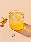 Refreshing iced yellow drink with cookie crumbs on pastel table
