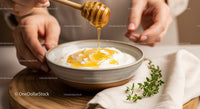 Creamy yogurt with honey drizzle and fresh herbs on rustic plate