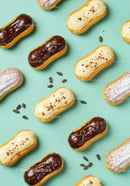Delicious chocolate and vanilla éclairs on turquoise background
