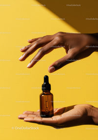 Elegant Hand Holding Brown Skincare Dropper Bottle on Yellow Background