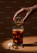 Hand pouring coffee into iced glass with beans