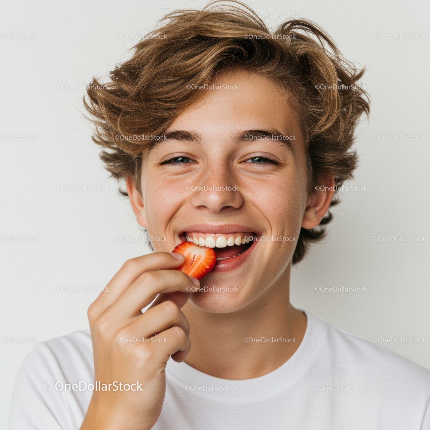 Joyful Teenage Boy Eating Strawberry in Bright White Background