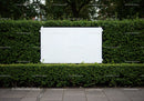 Blank white billboard surrounded by green hedge outdoors