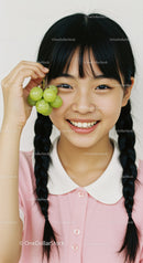 Young Girl with Braids Holding Green Grapes and Smiling Close-Up