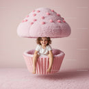 Smiling child sitting inside giant pink cupcake