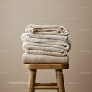 Stack of Soft Neutral Colored Blankets on Wooden Stool