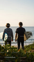 Young surfers with surfboards enjoying sunset by the ocean