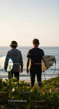 Young surfers with surfboards enjoying sunset by the ocean