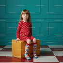 Little girl in red polka dot dress sitting indoors