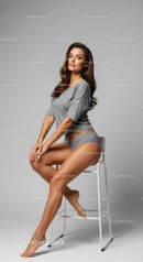 Elegant Woman Sitting on Stool in Casual Gray Outfit