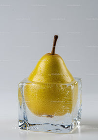 Fresh yellow pear frozen inside a clear ice cube