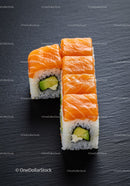 Fresh salmon sushi rolls with avocado on black slate