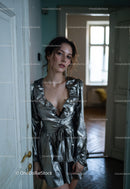 Elegant Woman in Silver Dress Standing in Rustic Interior