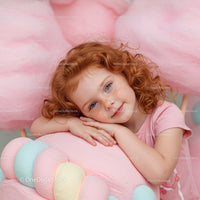 Little girl with curly hair resting on pastel decorations