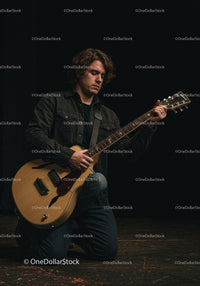 Man playing electric guitar on stage in dark setting