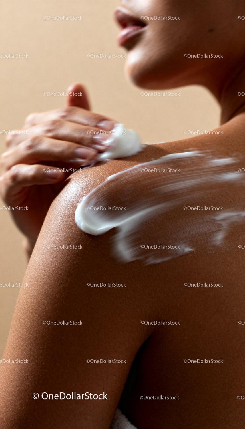 Woman applying moisturizing cream on smooth shoulder