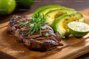 Juicy Grilled Steak with Fresh Avocado and Garlic on Rustic Board