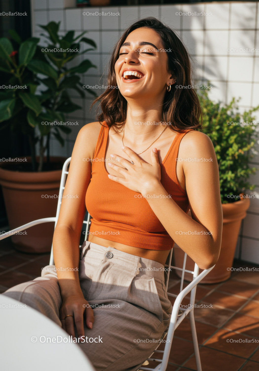 Joyful Woman Sitting Outdoors Laughing in Warm Sunlight on Terrace
